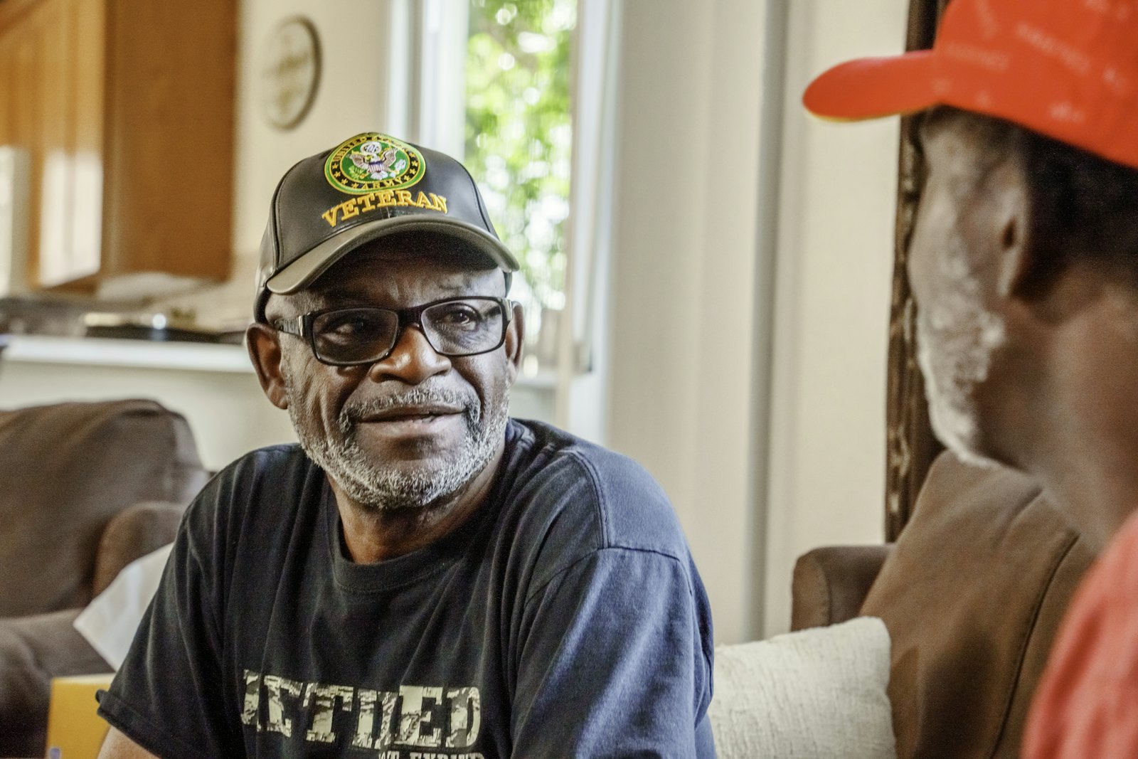 A veteran in a service cap smiling during a conversation